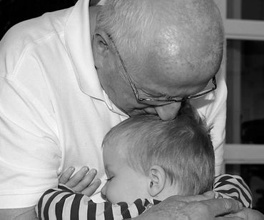 En gammel mand og en lille dreng giver hinanden et knus 