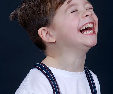 Dreng med seler griner op i luften