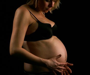 gravid kvinde i undertøj holder på sin mave